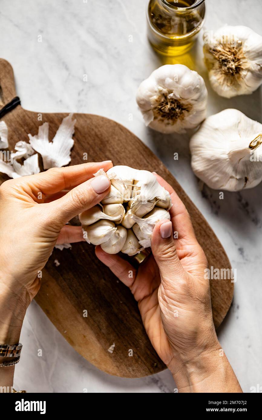 Fresh white garlic bulb and cloves. Hands preparing garlic Stock Photo