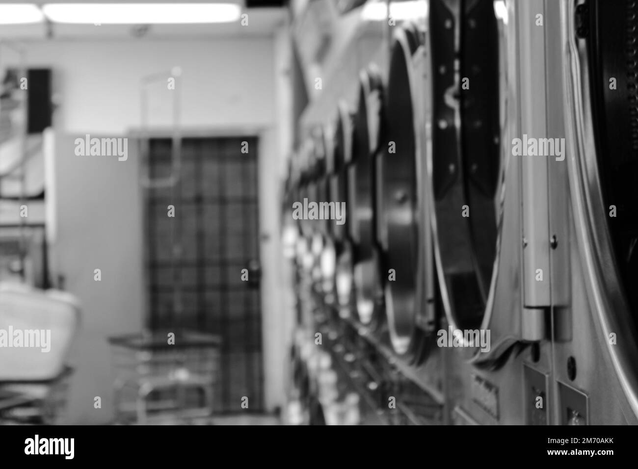 A grayscale shot of rows of laundry machines in a laundromat Stock Photo