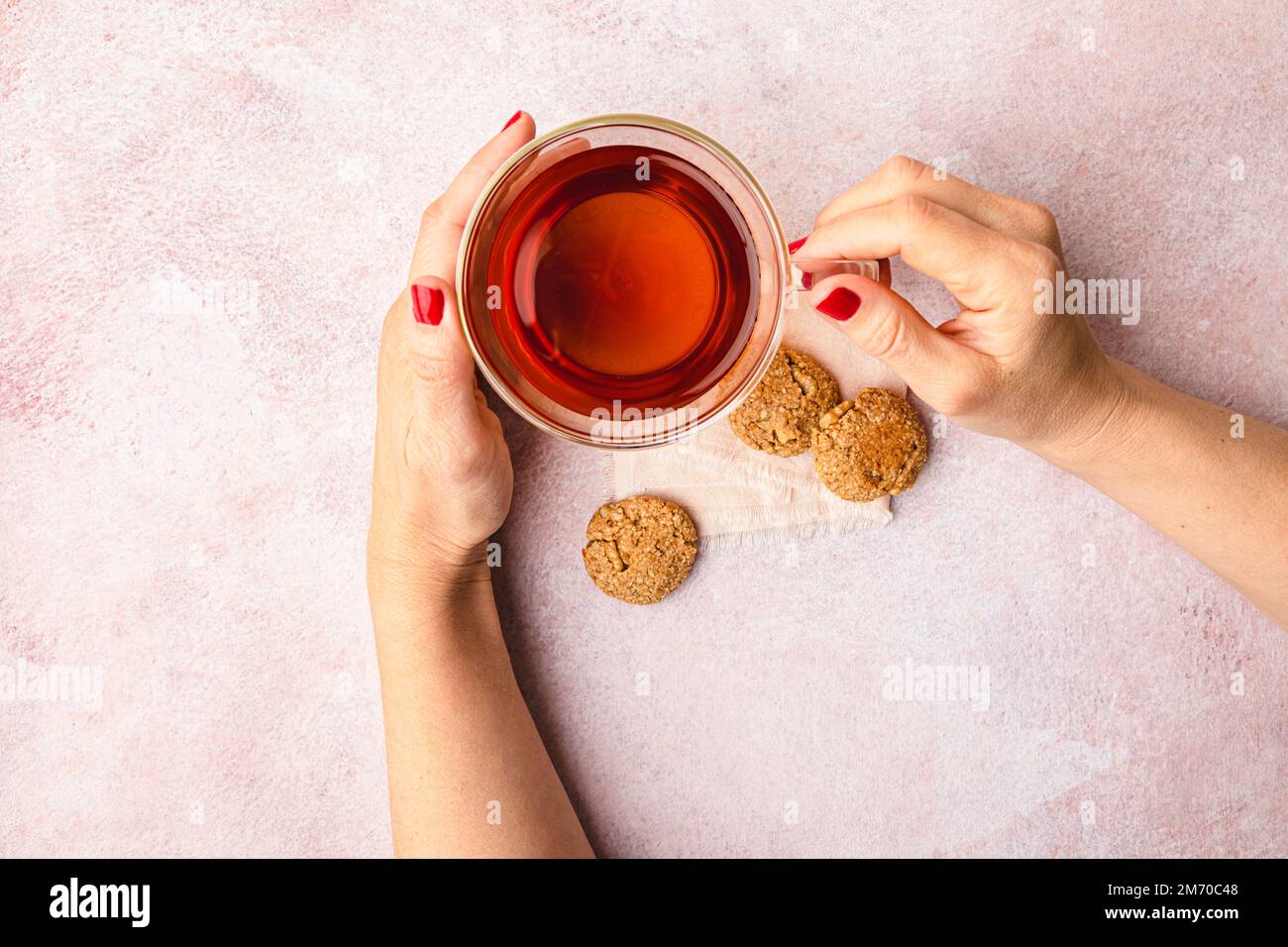 Cup of black tea with woman hands and homemade oats and walnut cookies. Stock Photo