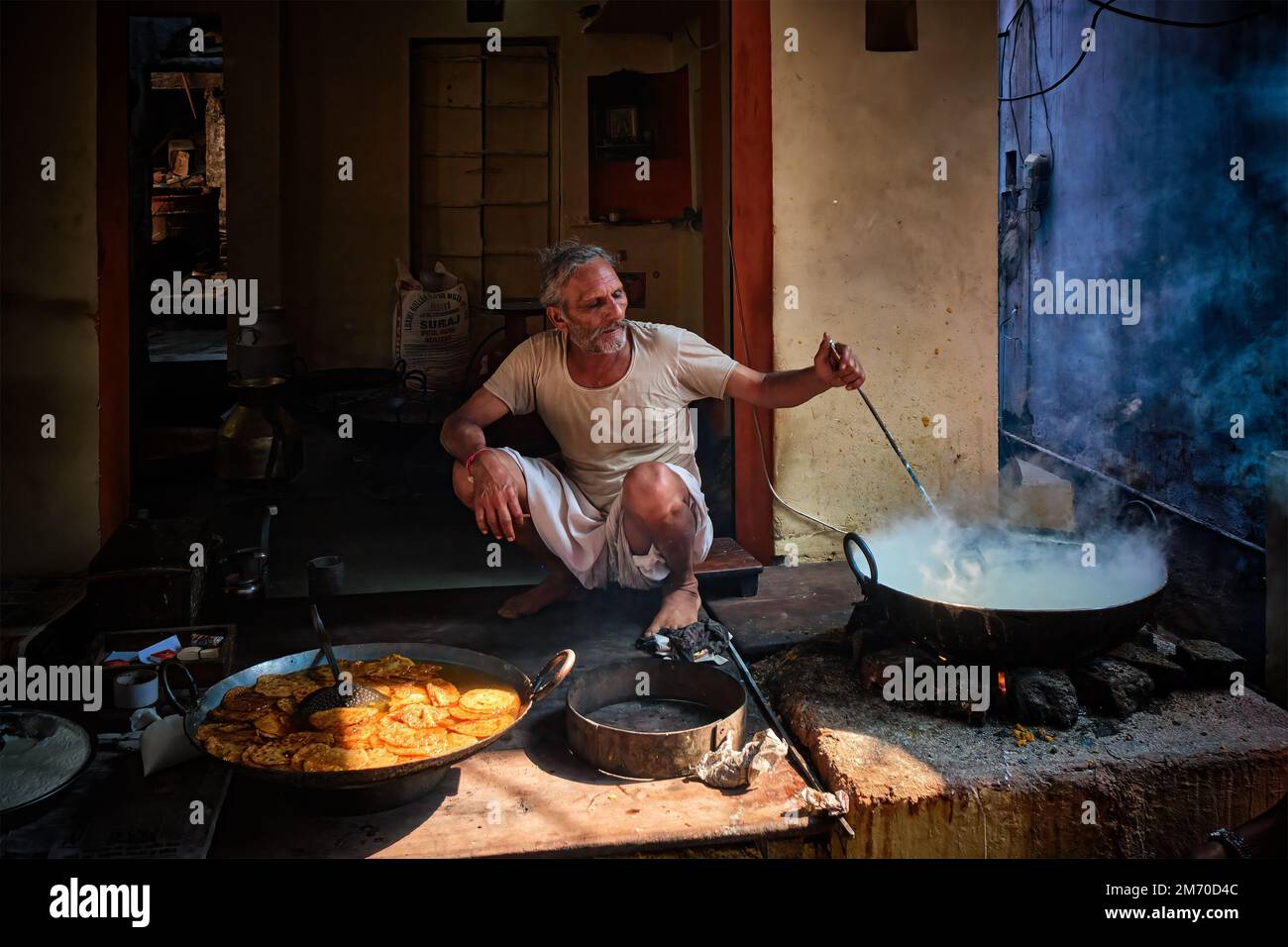 Pushkar, India - November 7, 2019: Street food stall cook cooking mixing with spoon sweet puri bread and rabri sweet, condensed-milk-based dish in str Stock Photo