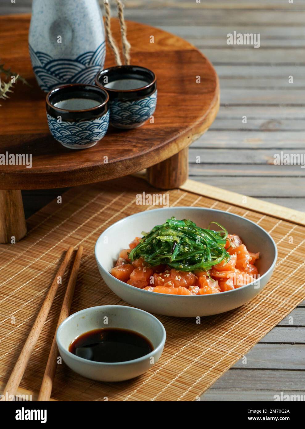 Japanese sake and salmon sashimi and wakame seaweed on asian wood table ...