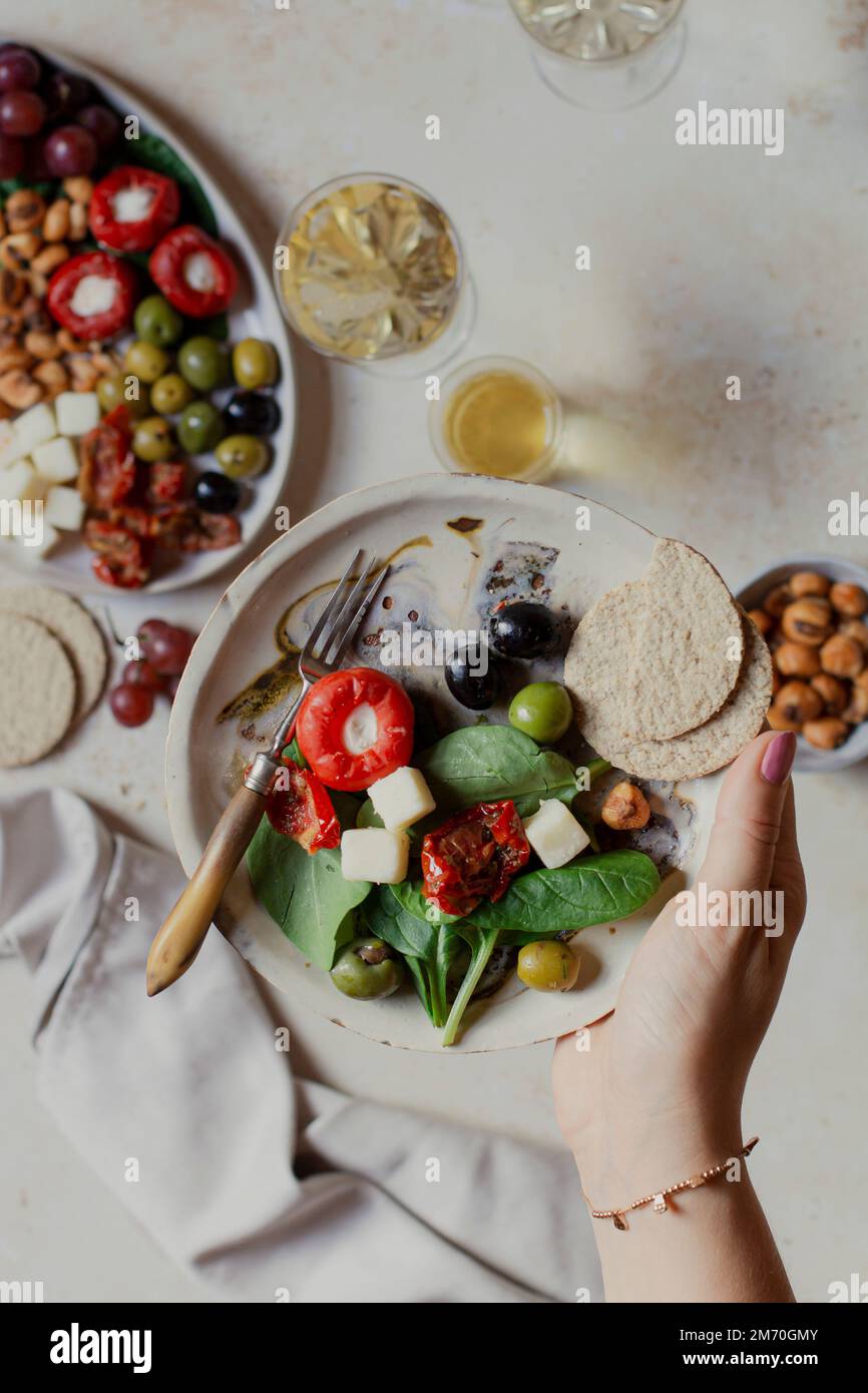 Antipasti platter in hand with oatcakes and white wine Stock Photo
