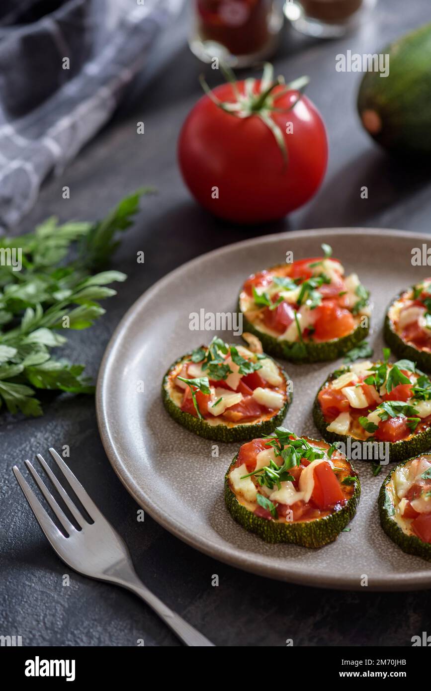 Baked zucchini with tomatoes and cheese on a plate. Stock Photo