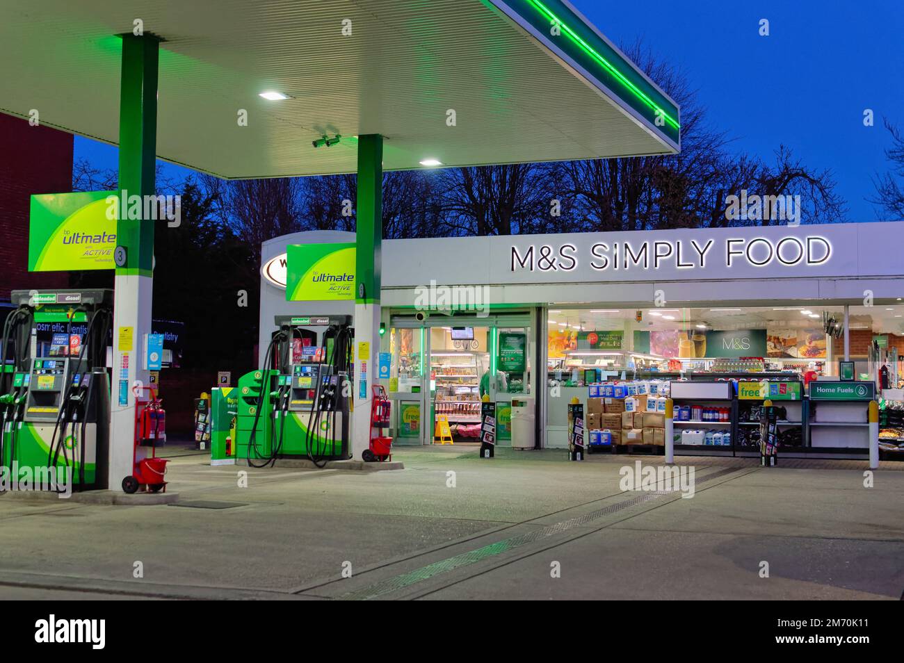 The forecourt of the BP petrol station at dusk with a Marks and Spencer Simply Food outlet shop in Shepperton High Street Surrey England UK Stock Photo