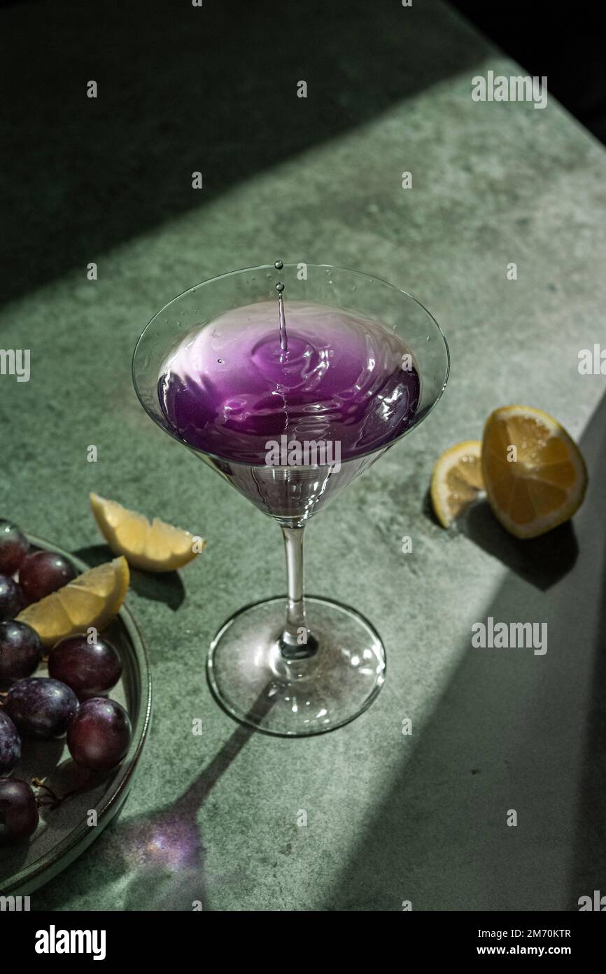 Martini glass with purple drink on green background Stock Photo