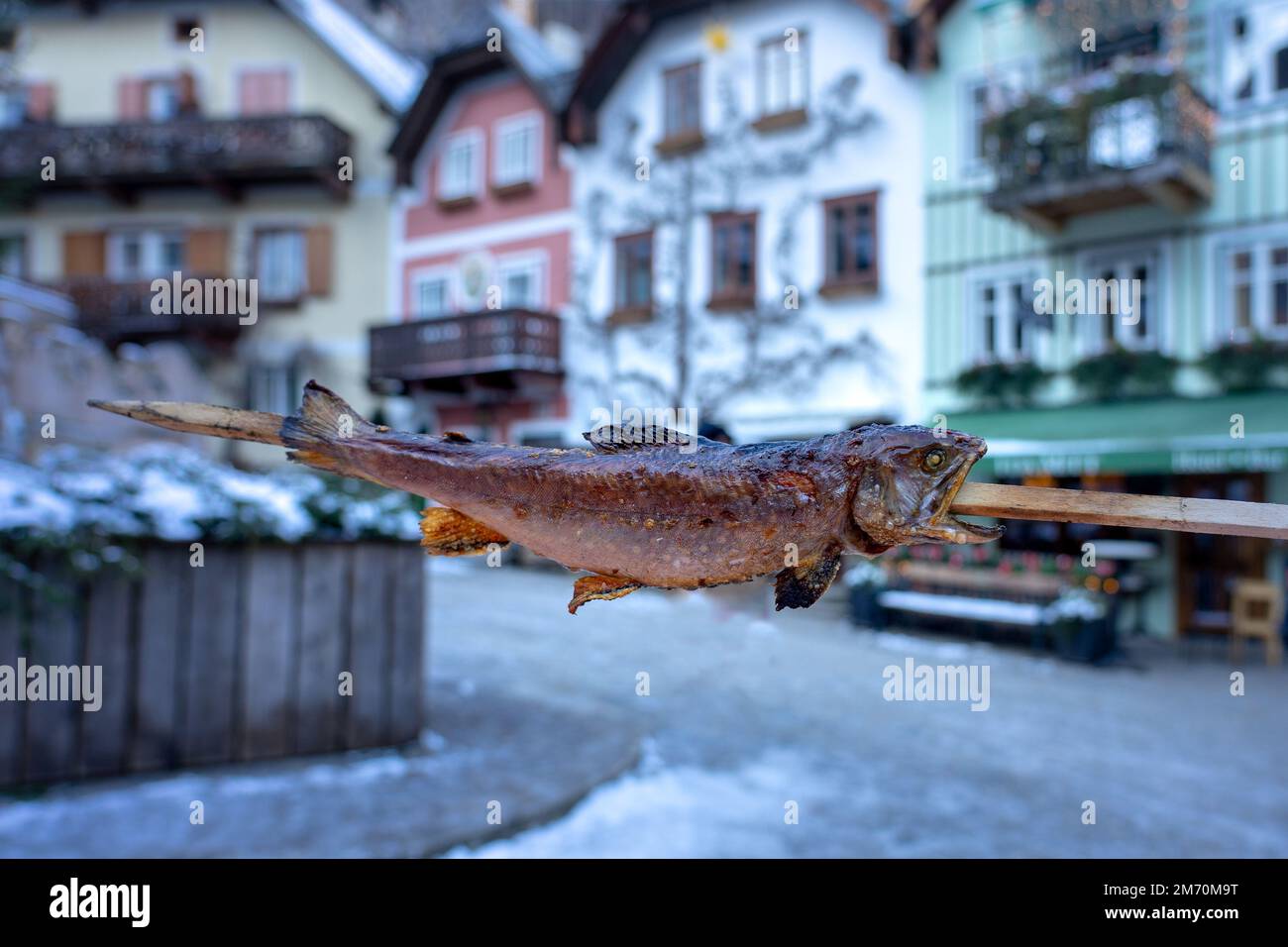 eating skewered fish in Hallstatt at the christmas market on main square . Stock Photo