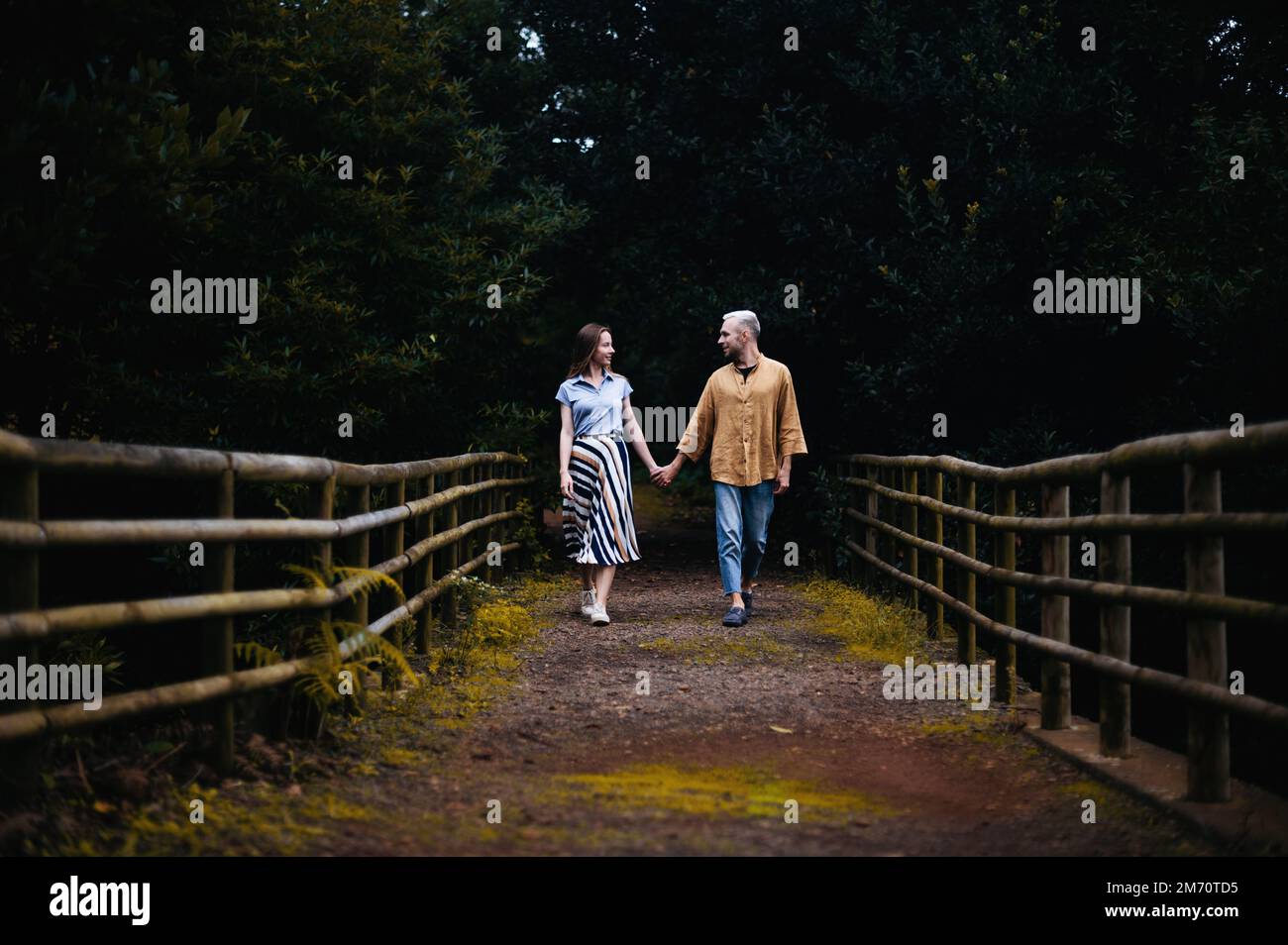 A romantic photo of a young couple in a beautiful park, walking hand in ...