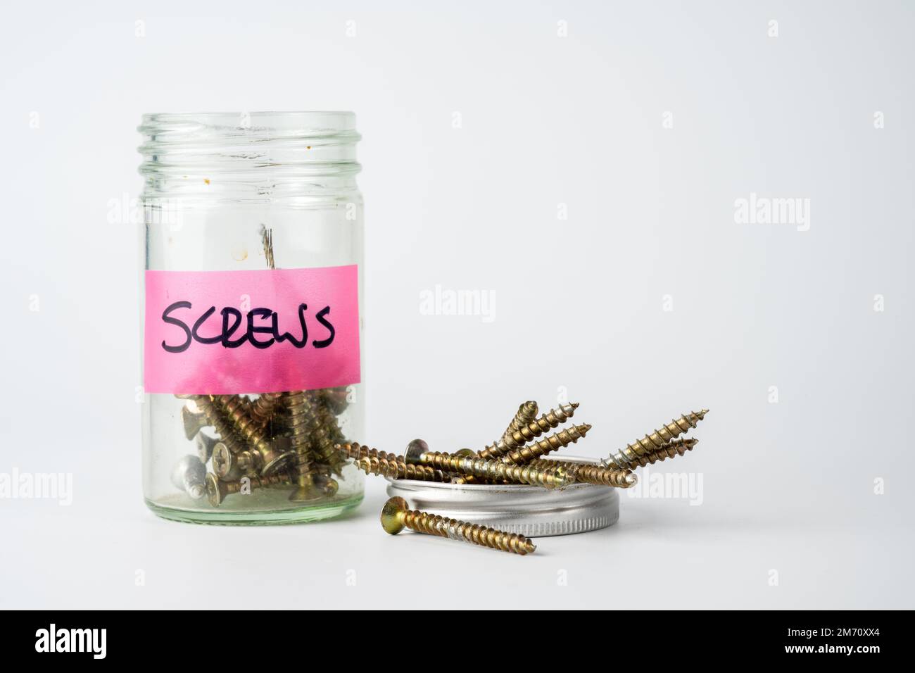 jar of woodworking screws with the screw top off and filled with screws
