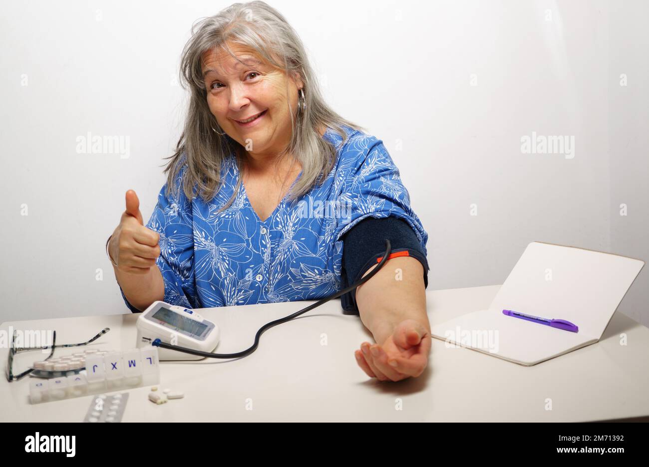 Woman taking her blood pressure with a nod of approval everything ok Stock Photo