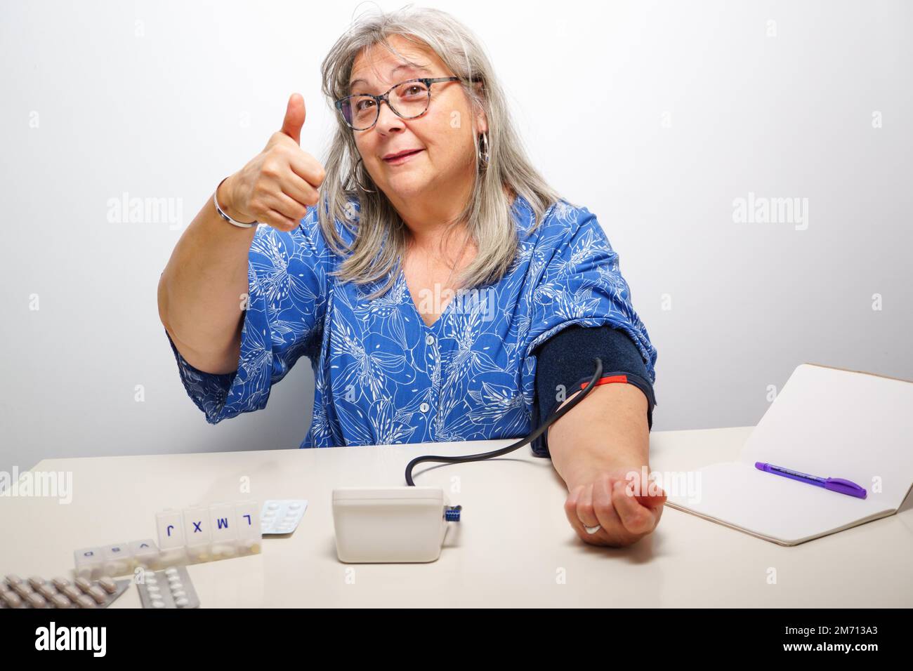 Woman taking her blood pressure with a nod of approval everything ok Stock Photo