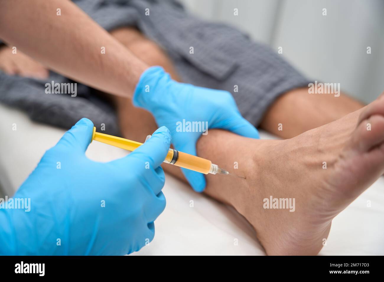 Qualified medical specialist performing a biopsy sampling from ankle