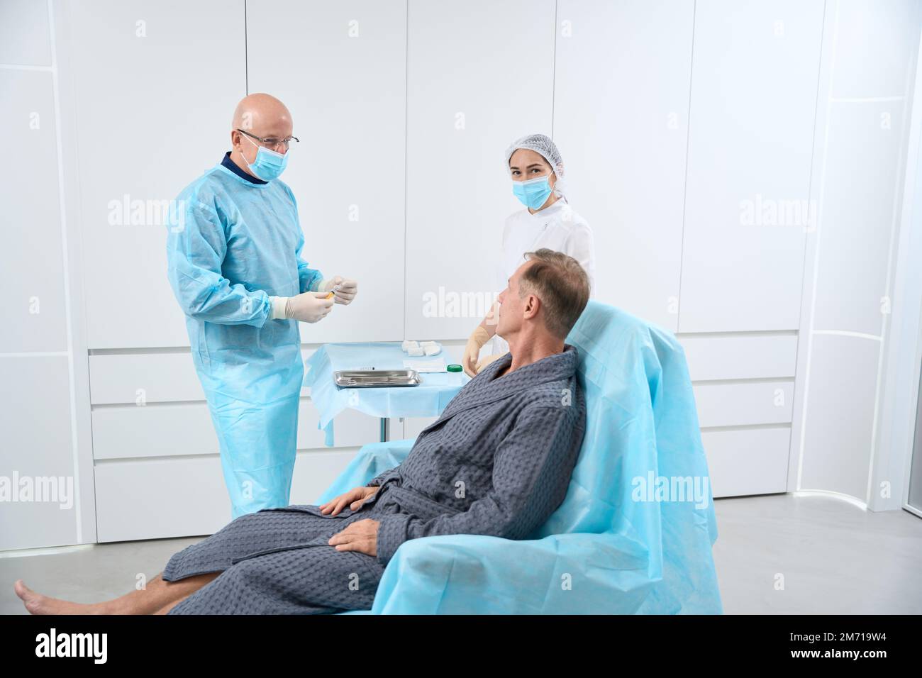 Professional medical staff preparing to treat patient in hospital robe