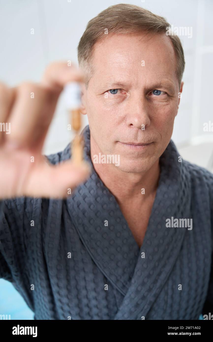 Serious man holds ampoule with modern medicine in his hands Stock Photo