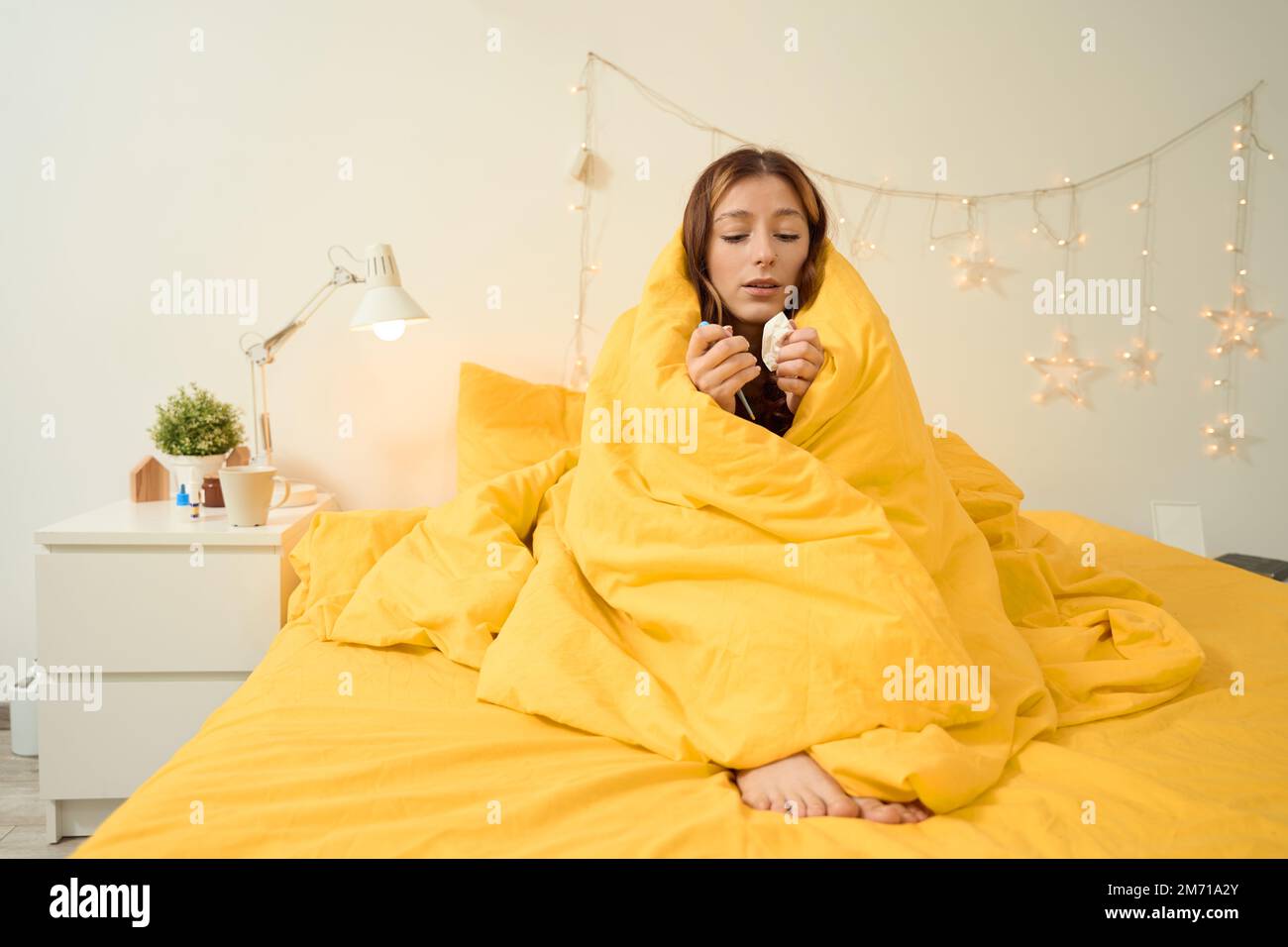 Sick female wrapped in blanket sitting in bedroom Stock Photo Alamy