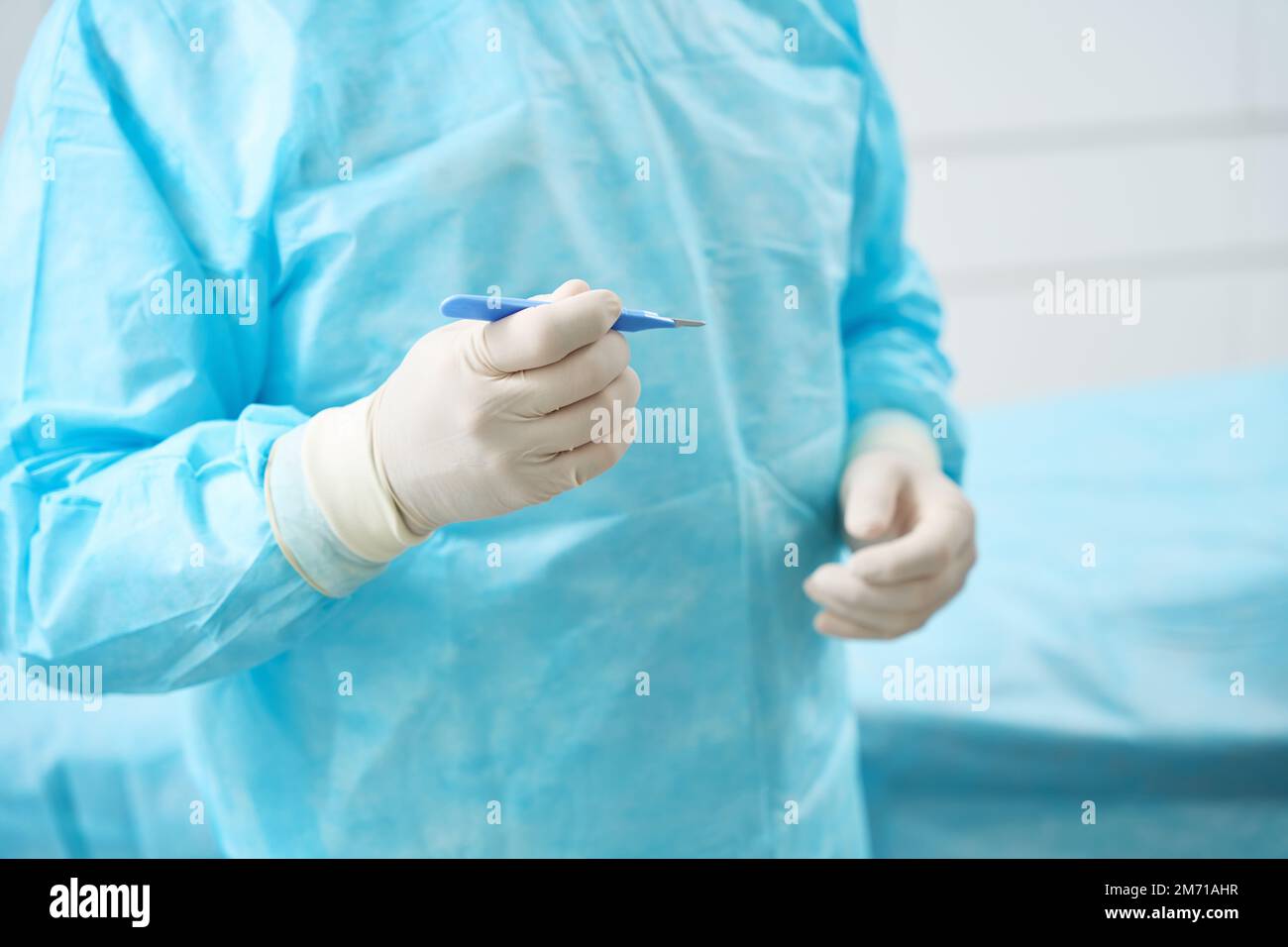 Doctor holds in his hand surgical instrument with blue handle Stock Photo