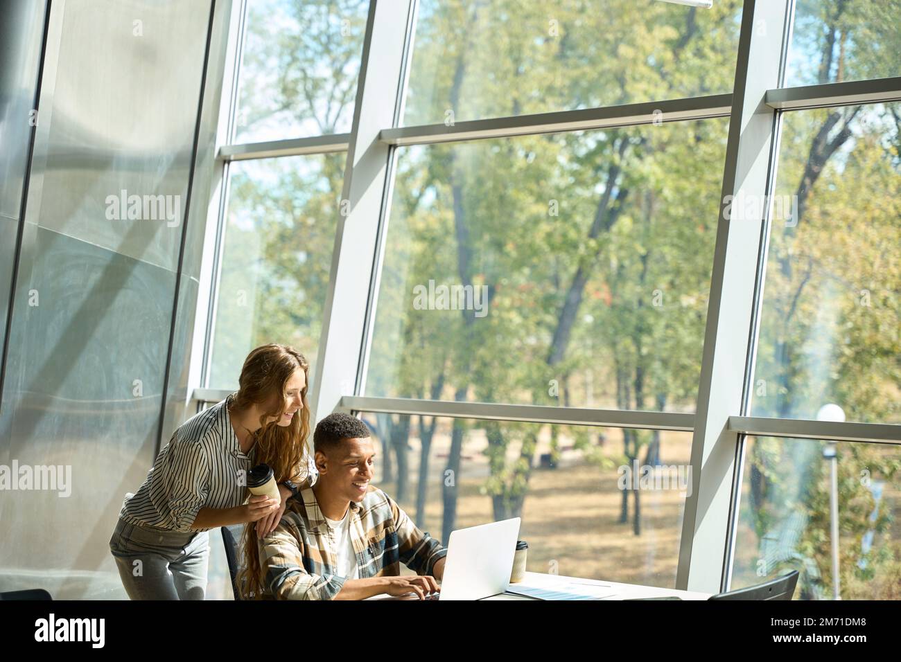 Happy coworkers working together while using laptop Stock Photo