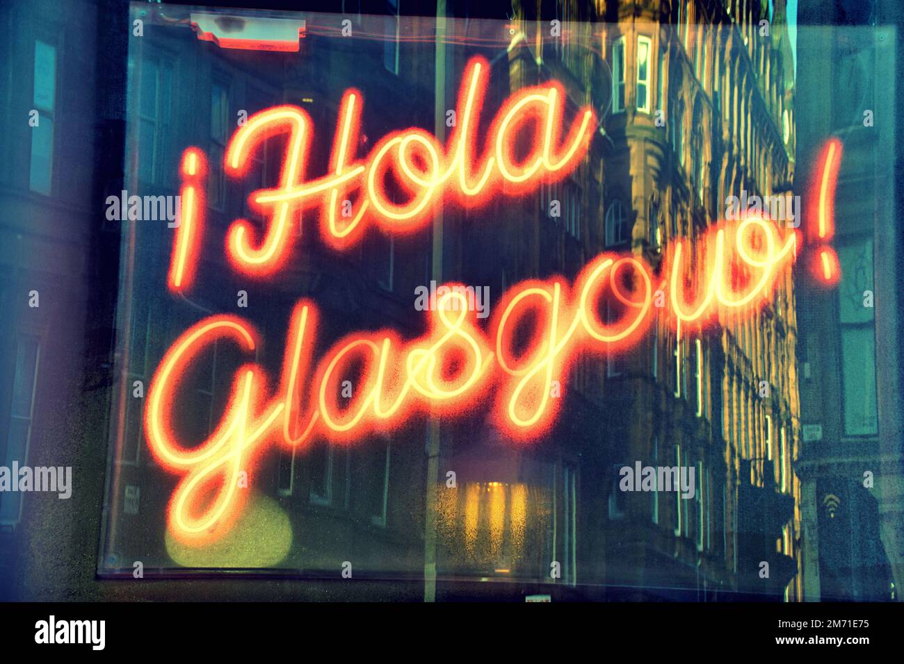 Hola Glasgow neon sign with tenement reflection in window  in Spanish hello Stock Photo