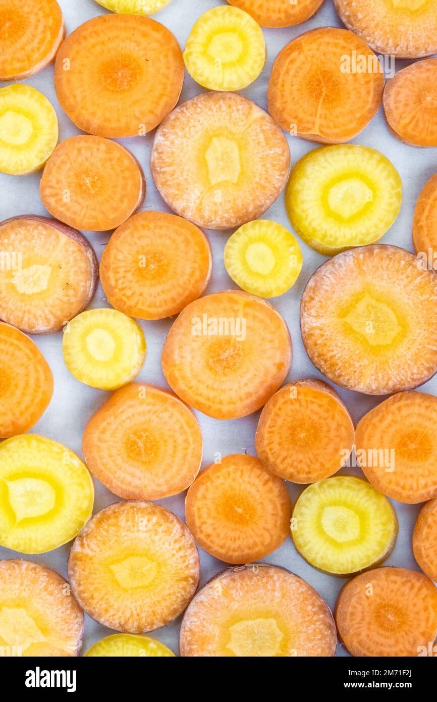 A close up of sliced yellow and orange carrots seen overhead displayed in a geometric pattern. Stock Photo