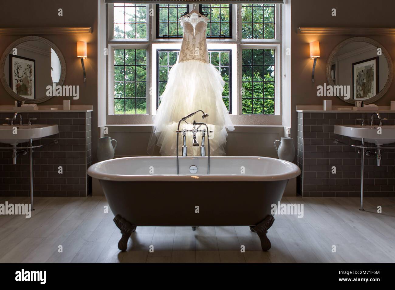A luxury bathroom with beautiful wedding dress hanged on the window ...