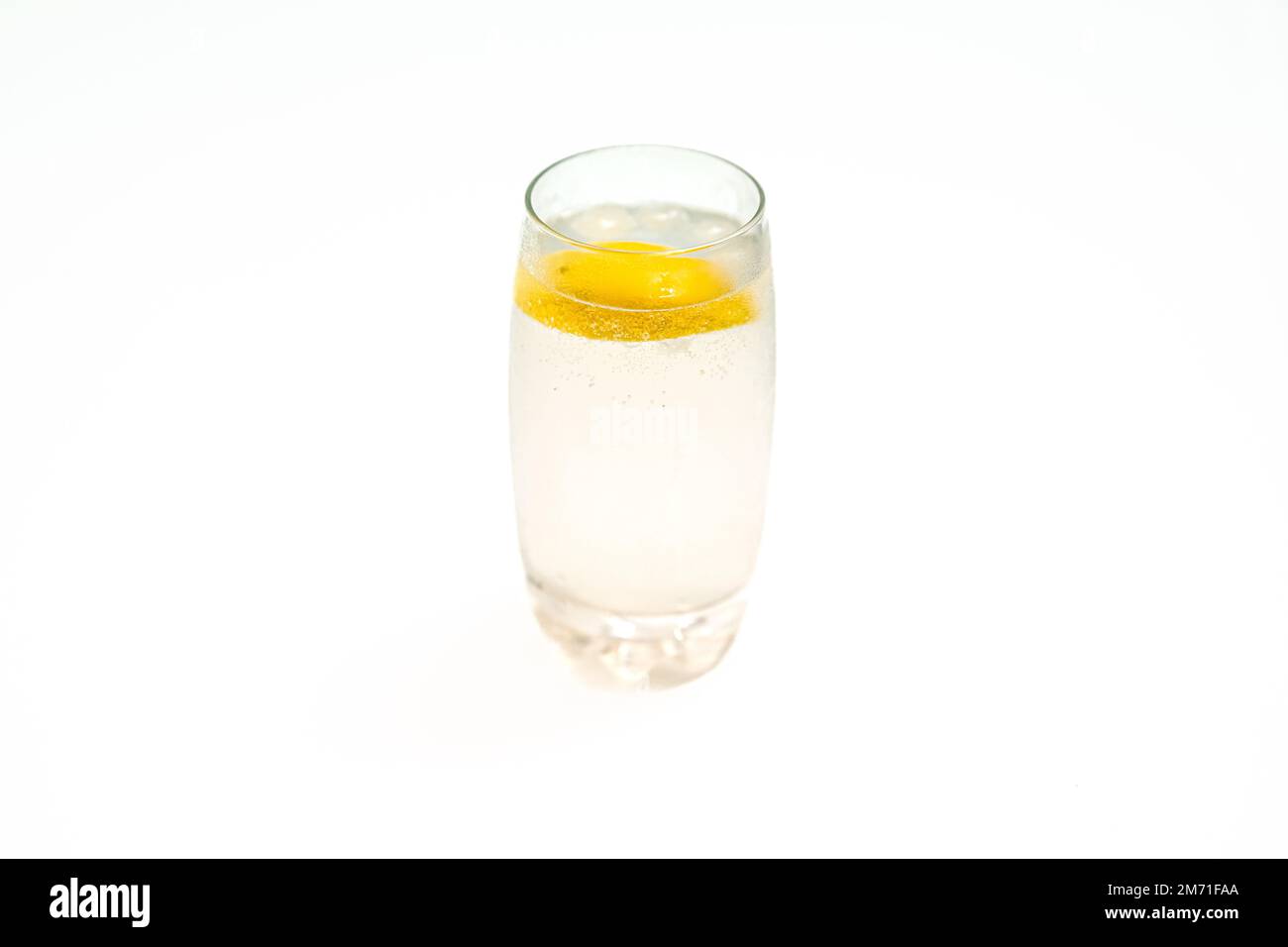 Glass cup with sparkling water and lemon. White background. Citrus