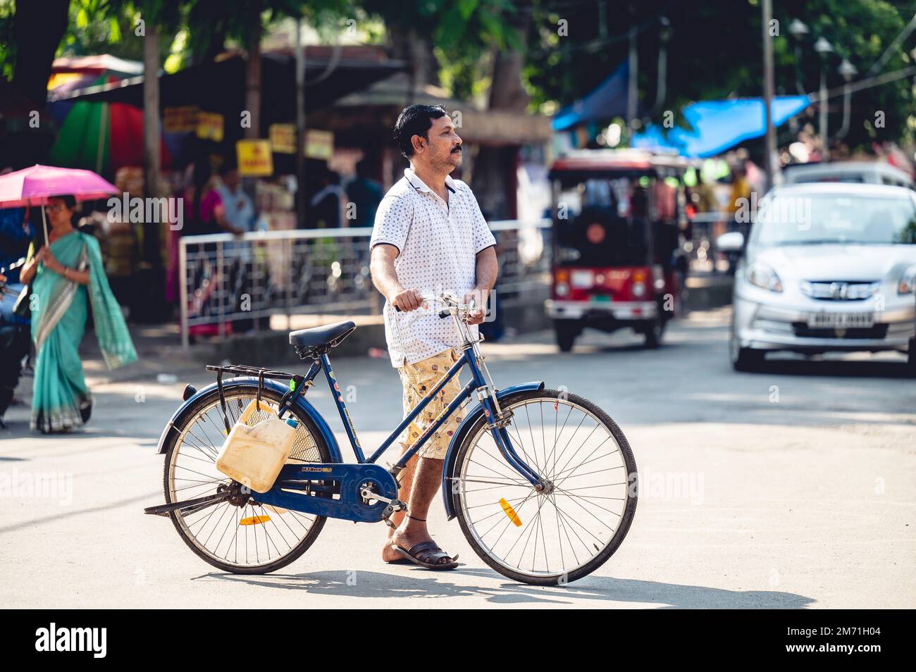 An Indian male walking with a bike in Visakhapatnam Vizag on a sunny