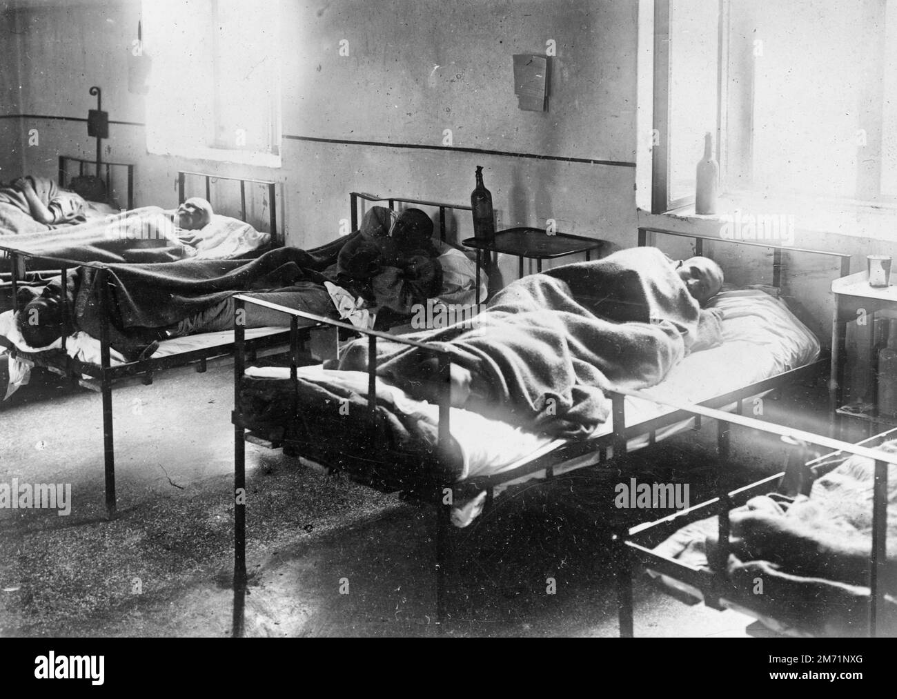 Typhus patients two in a bed. Impromptu typhus hospital equipped by the American Red Cross near Bucharest. The beds are cots of Army type, manufactured in Philadelphia. At the time this photograph was taken the hospital was so crowded that the patients were being put two in a bed head to foot - August 1919 Stock Photo