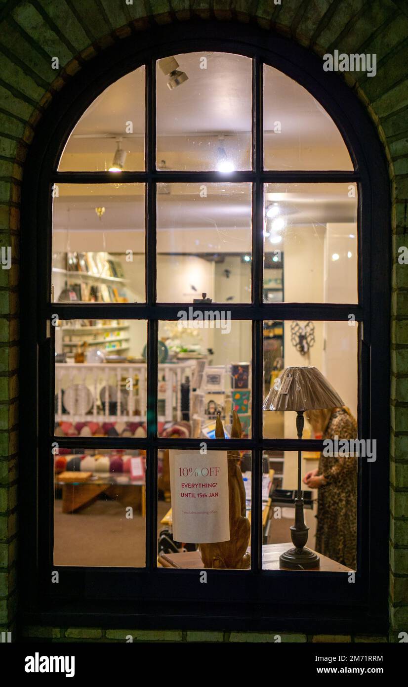 Old arched shop window at night with sale sign in Saffron Walden Stock