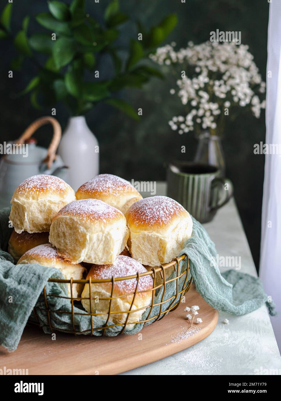 Homemade milk and creamcheese buns in a basket with a cloth next to a window Stock Photo