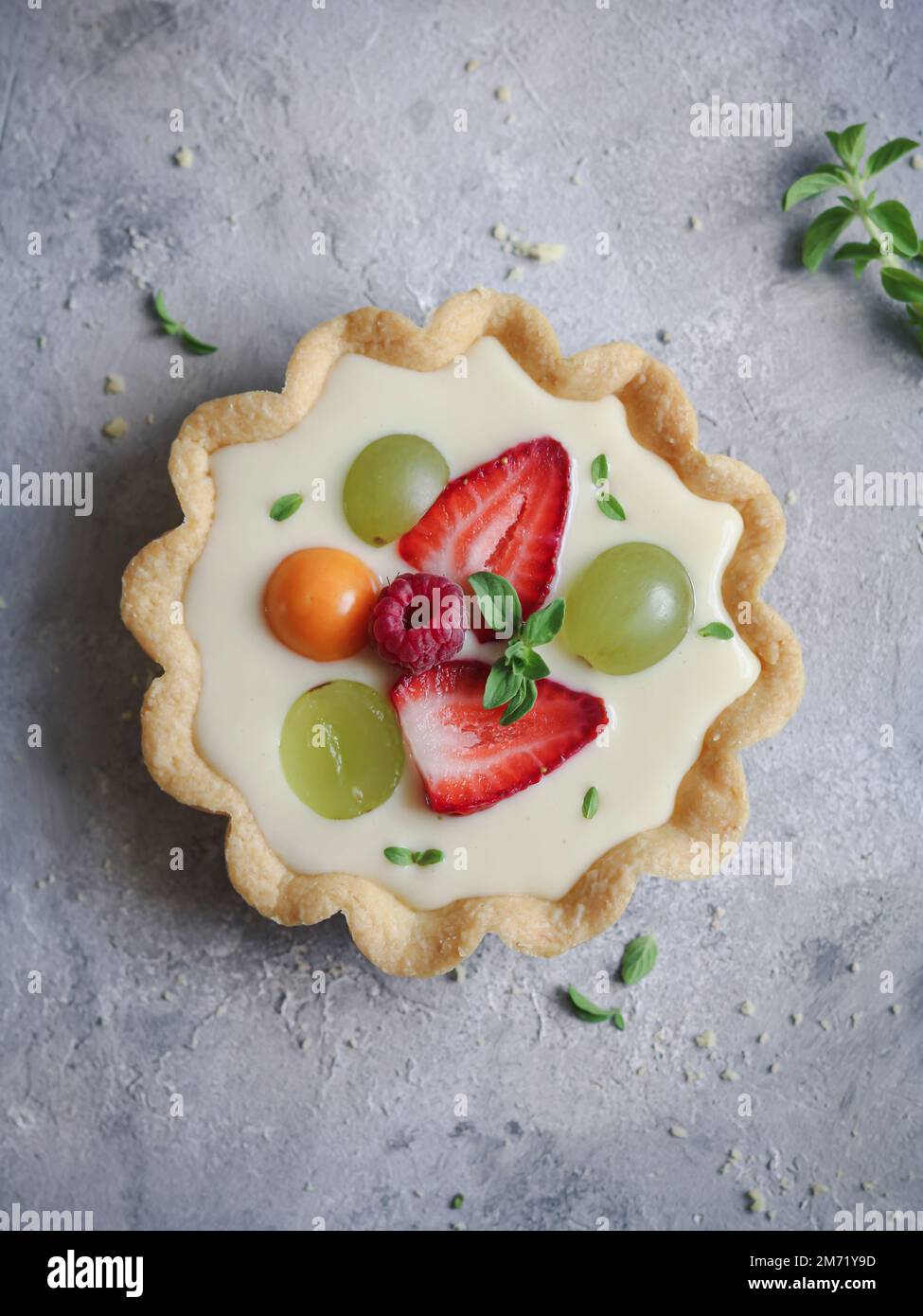Fresh fruit and custard cream tart decorated with mint leaves Stock Photo