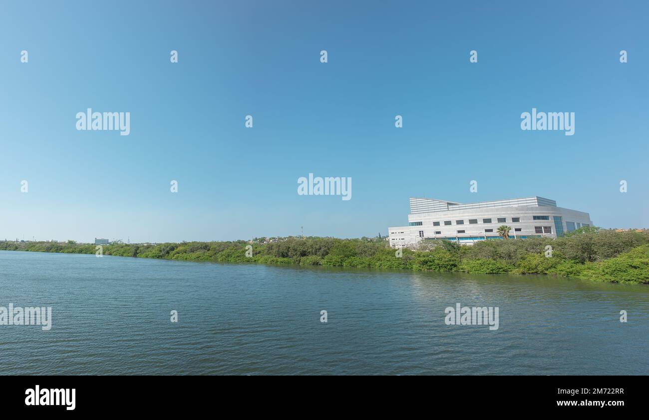 lake with calm water, green trees, blue sky and a building in the background, laguna del carpintero in tampico tamaulipas, cloudless vacation spot, no Stock Photo