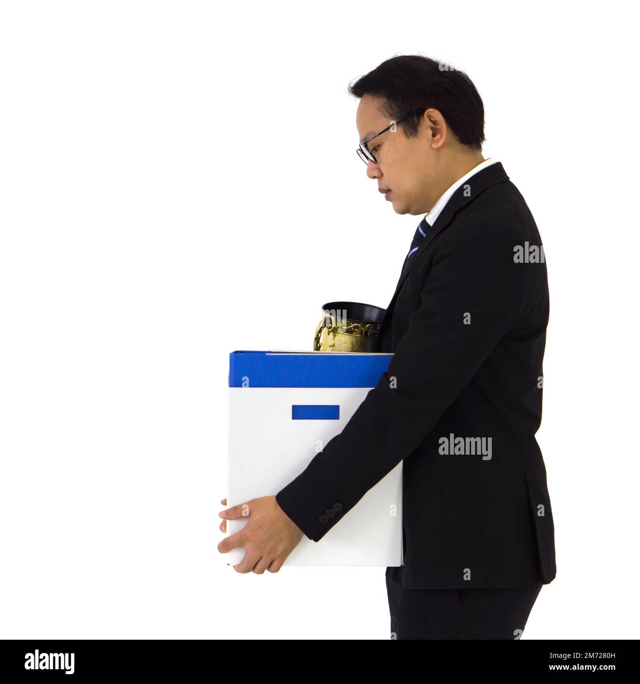 Asian senior manager in black suit feel sad, stressed and unhappy face holding paper box of belongings collected from office in the get fired day. Ide Stock Photo