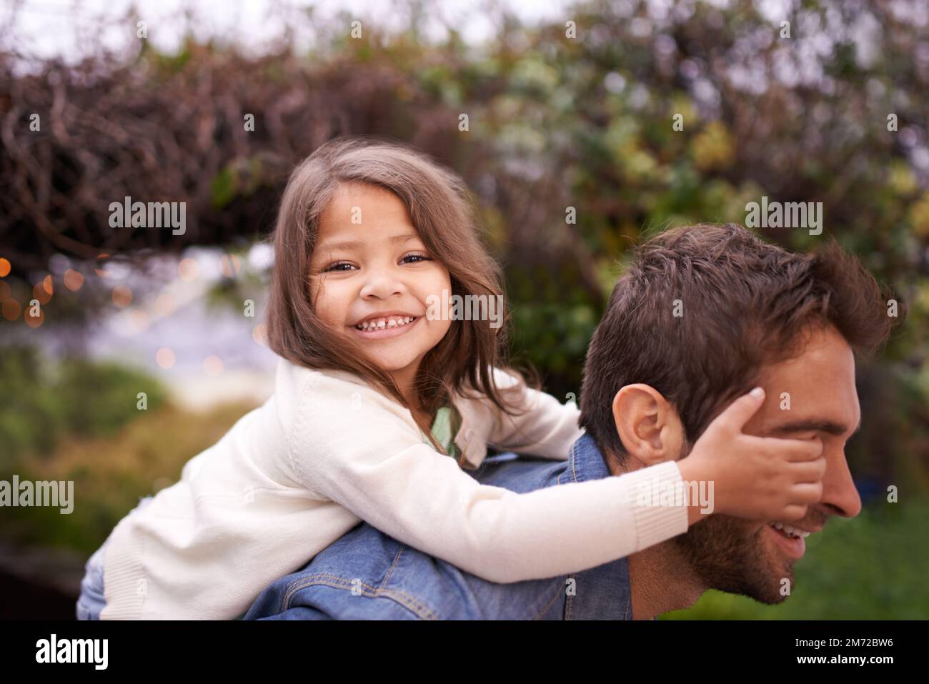 Think he knows its me. a little girl and her father playing outdoors. Stock Photo