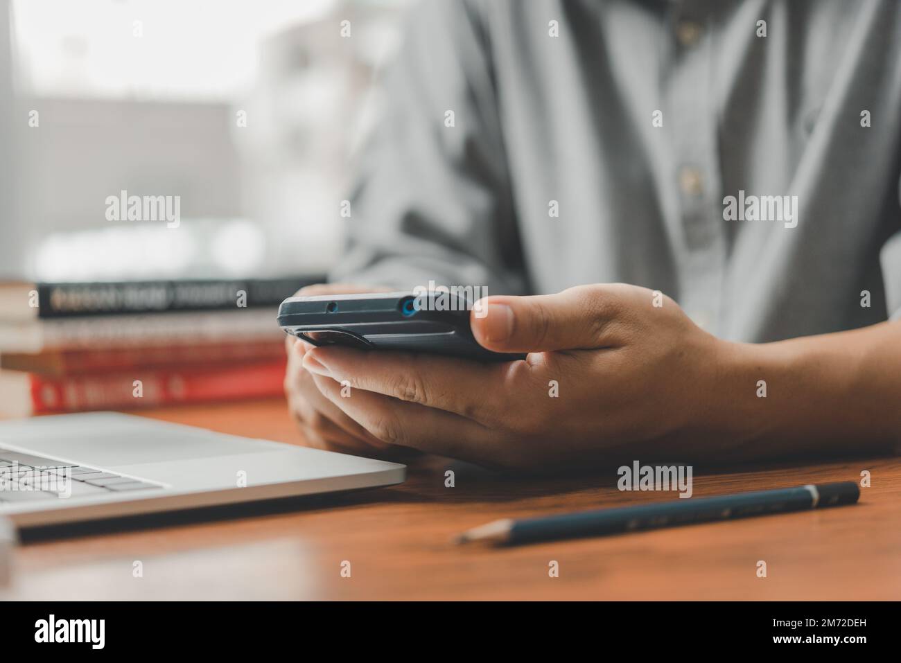 Man with mobile phone and laptop in office. Freelancer at work. Stock Photo