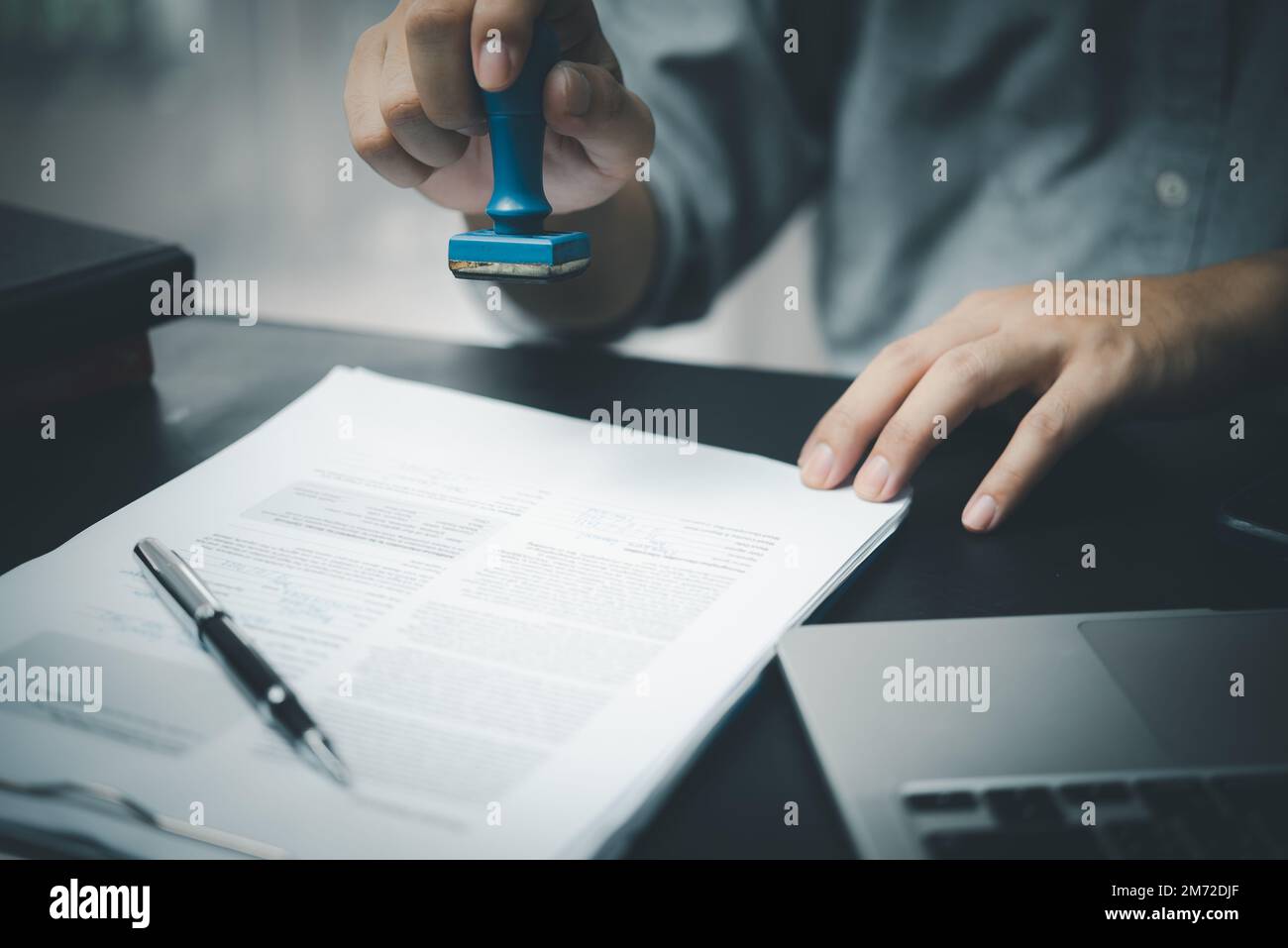 Man stamping approval of work finance banking or investment marketing documents on desk. Stock Photo