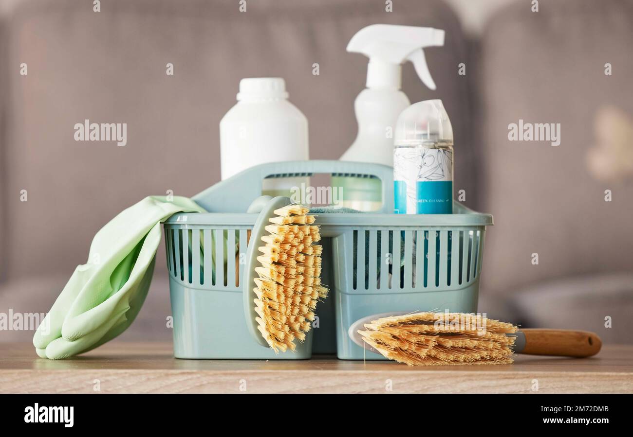 Product, basket and cleaning with a brush, supplies or detergent on a wooden table surface for housework. Bacteria, living room and empty room with a Stock Photo