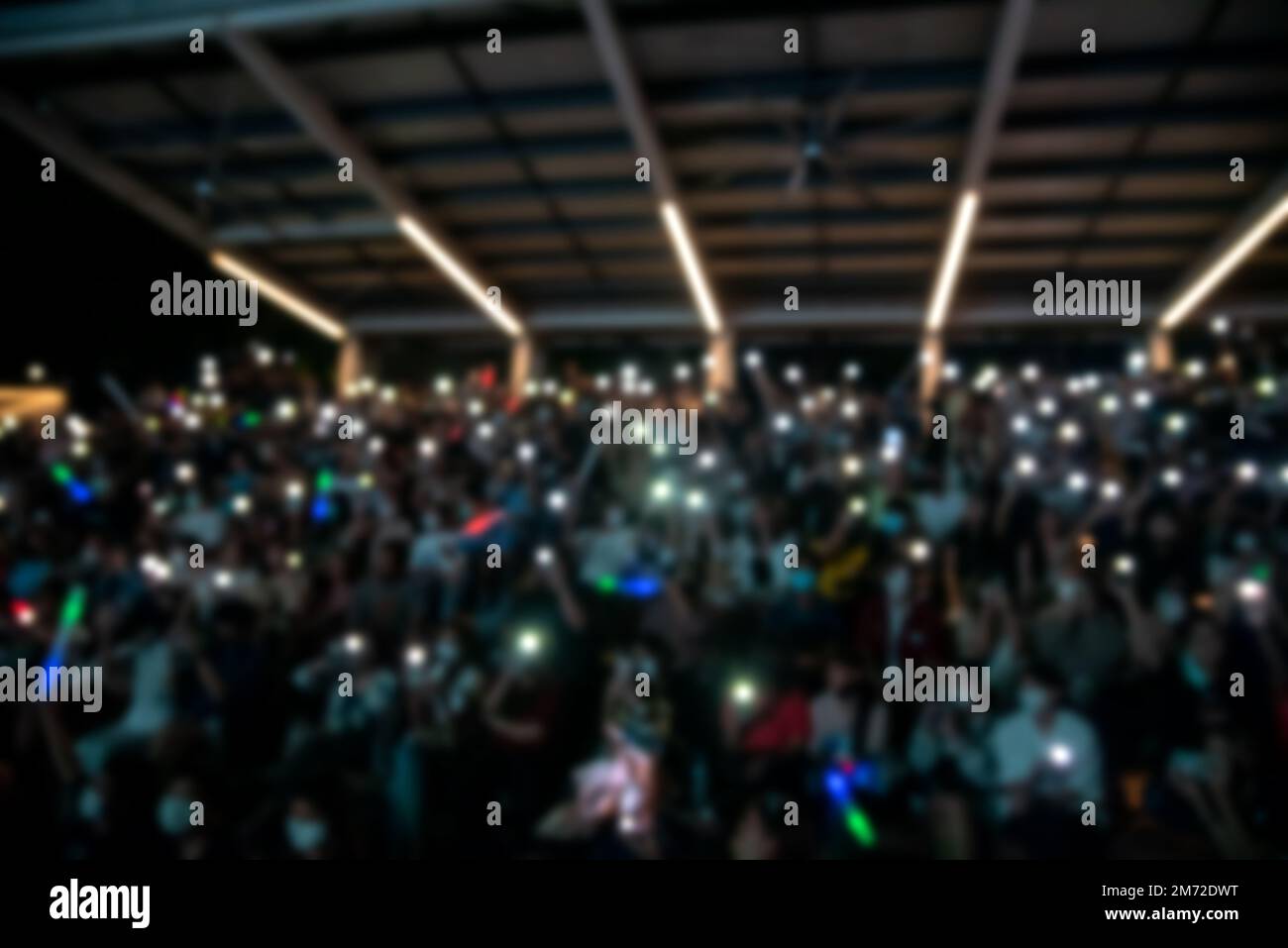 people holding cigarette lighters and mobile smartphones at a concert Stock Photo