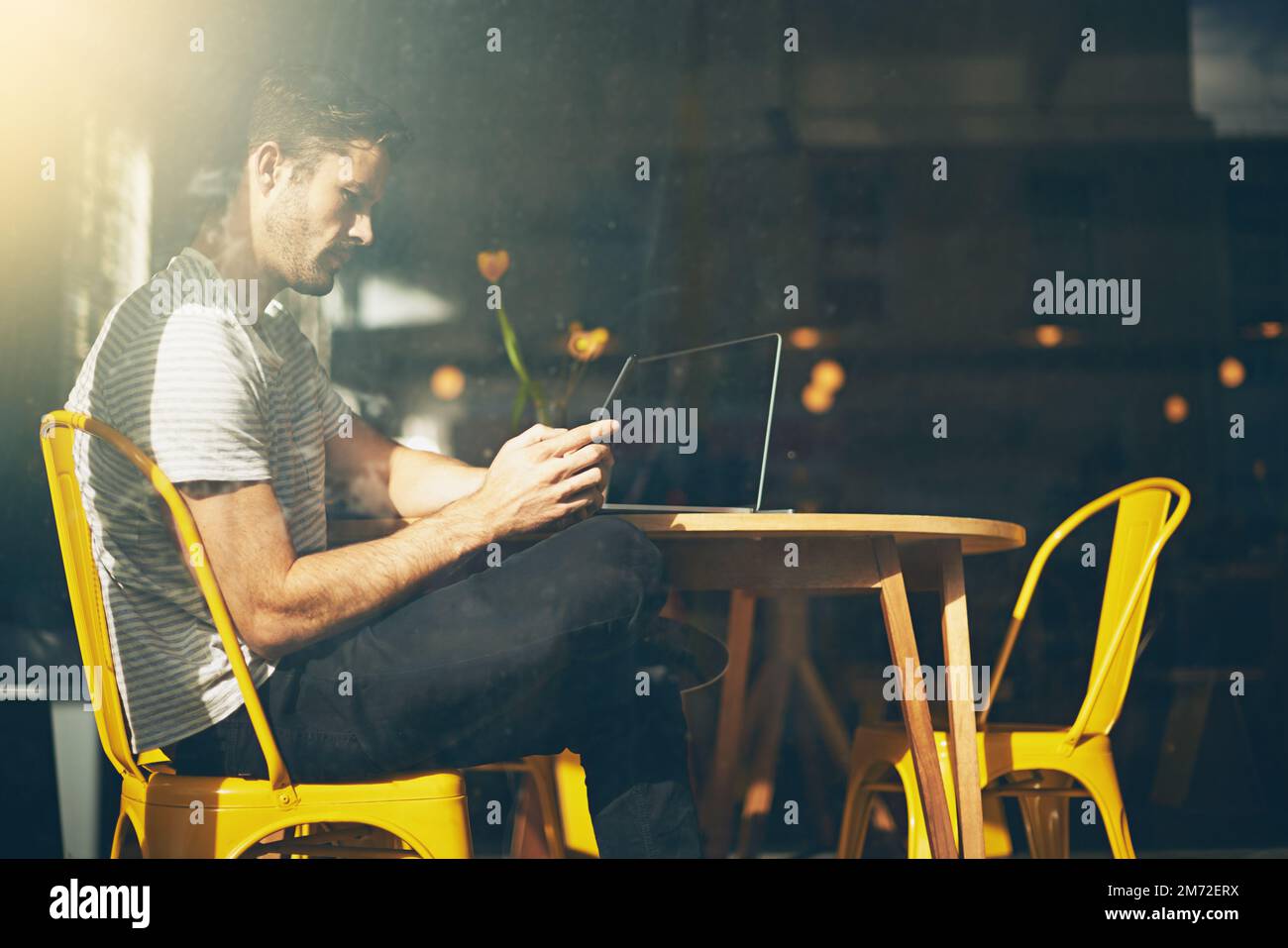 Chilling at his local cafe. A young man using his cellphone in a coffee shop. Stock Photo