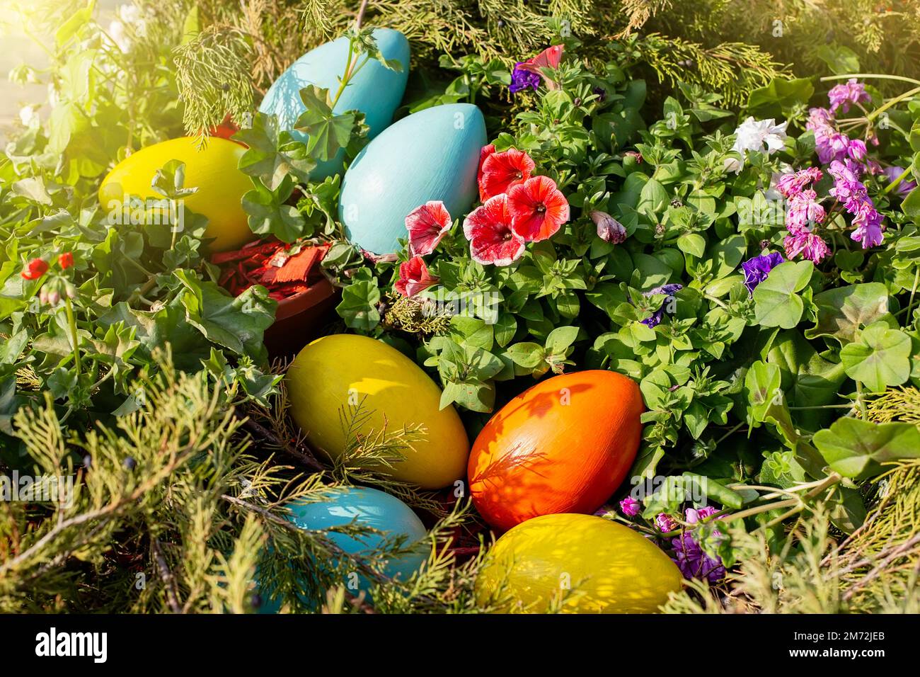 Large multi-colored wooden eggs lie on a flower bed , view from above Stock Photo