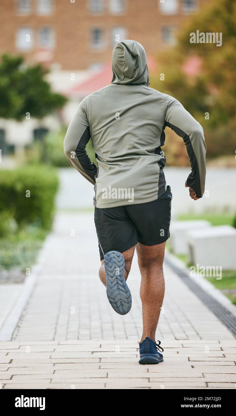 Fitness, back and black man running in city in winter for health, wellness and strength. Sports, exercise and male runner training, cardio jog or Stock Photo