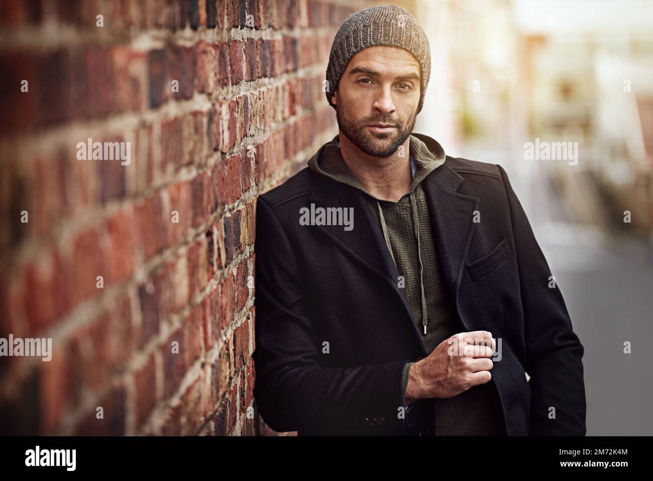 This town, its who I am. a handsome young man in trendy winter attire against a brick wall. Stock Photo