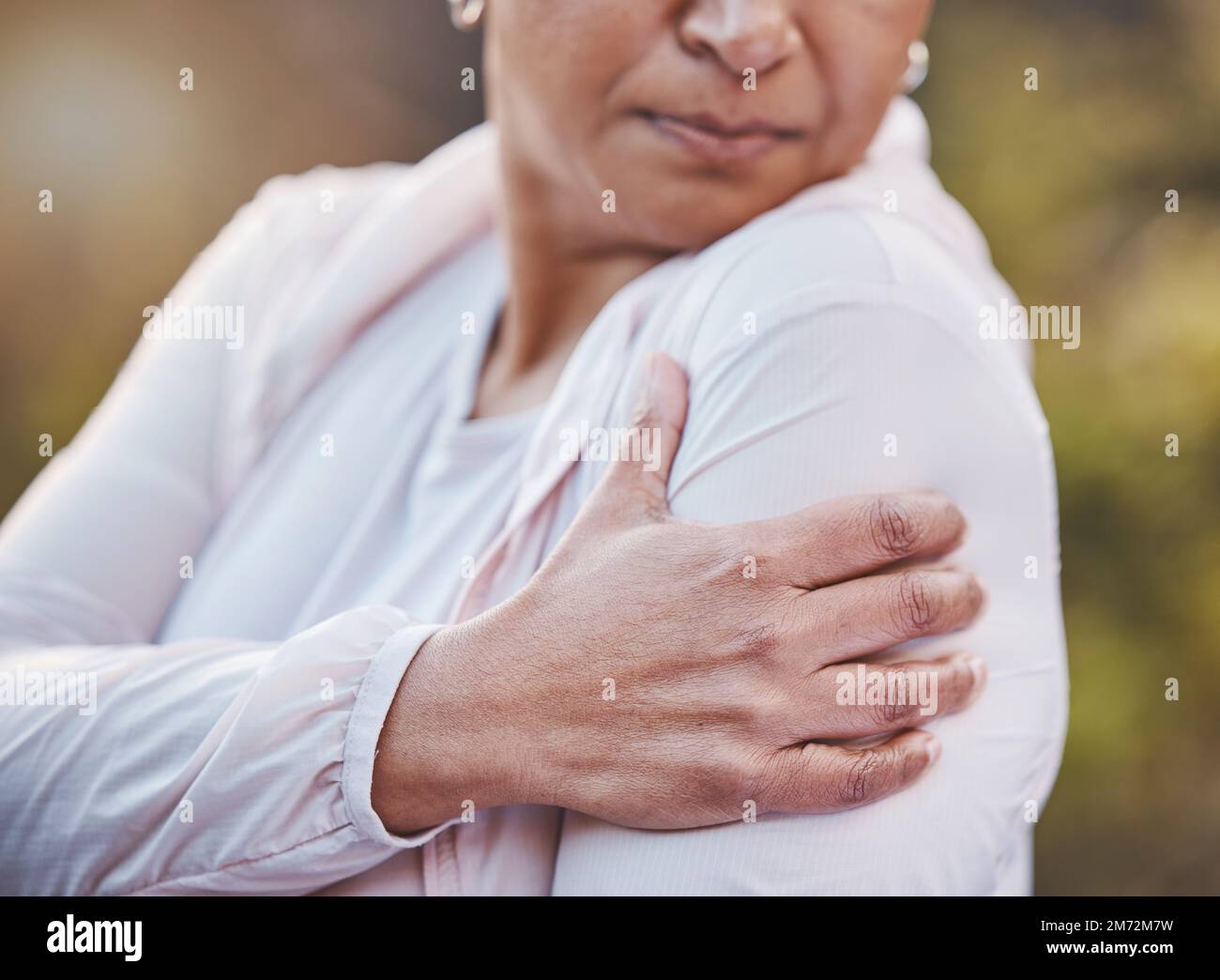 Senior woman, sports injury and shoulder pain at park after accident. Wellness, health and hand of elderly female on arm with muscle inflammation or Stock Photo