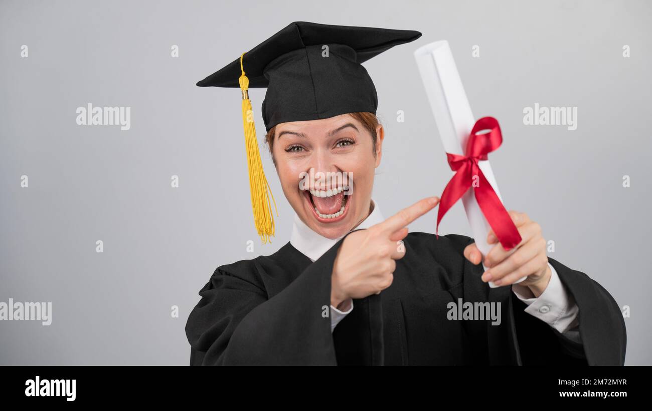 Graduation Received Happy woman in graduate gown pointing finger at received diploma Stock ...
