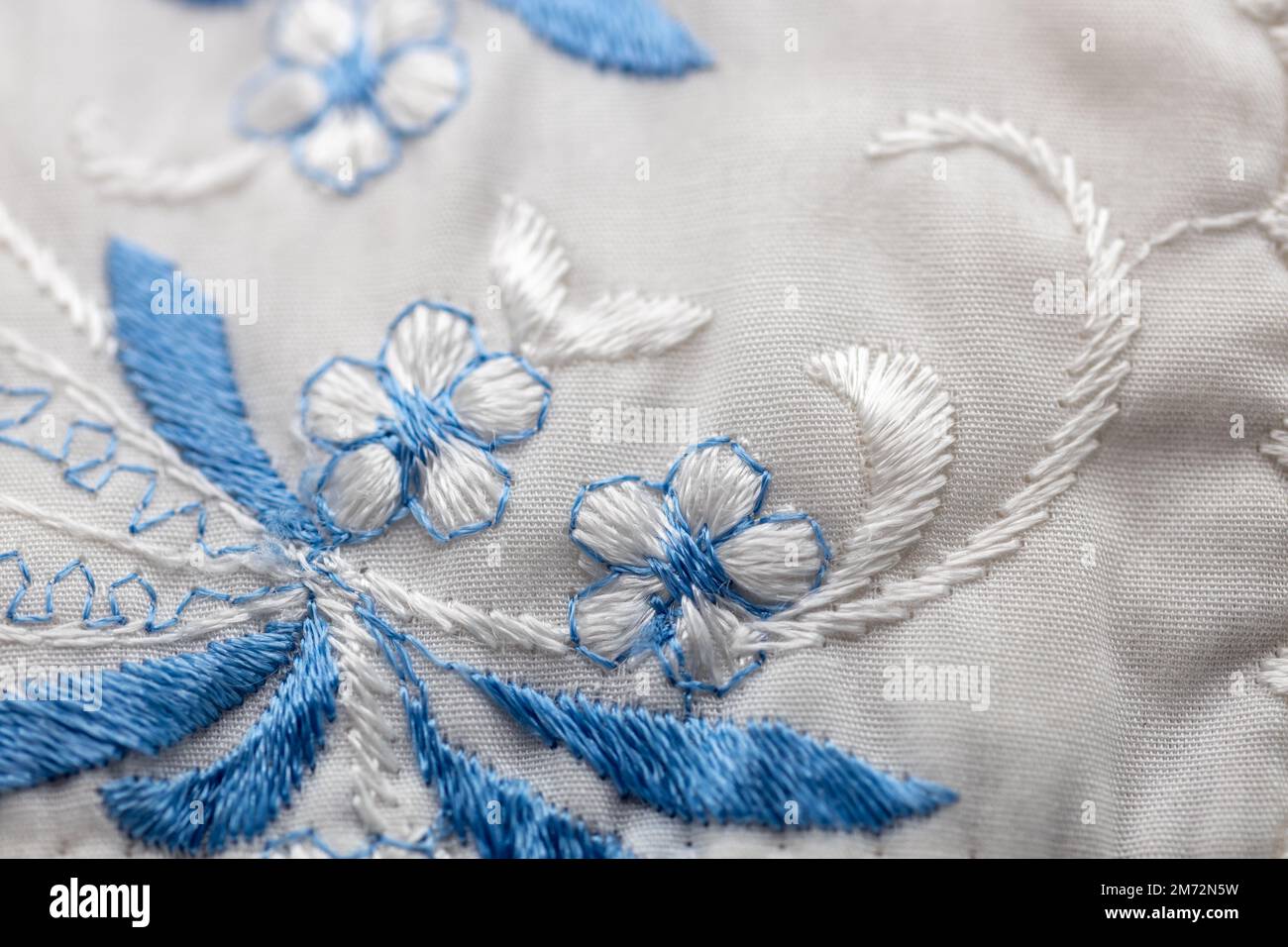 Macro abstract texture background of a blue and white needlepoint crafted flower pattern on white cloth Stock Photo