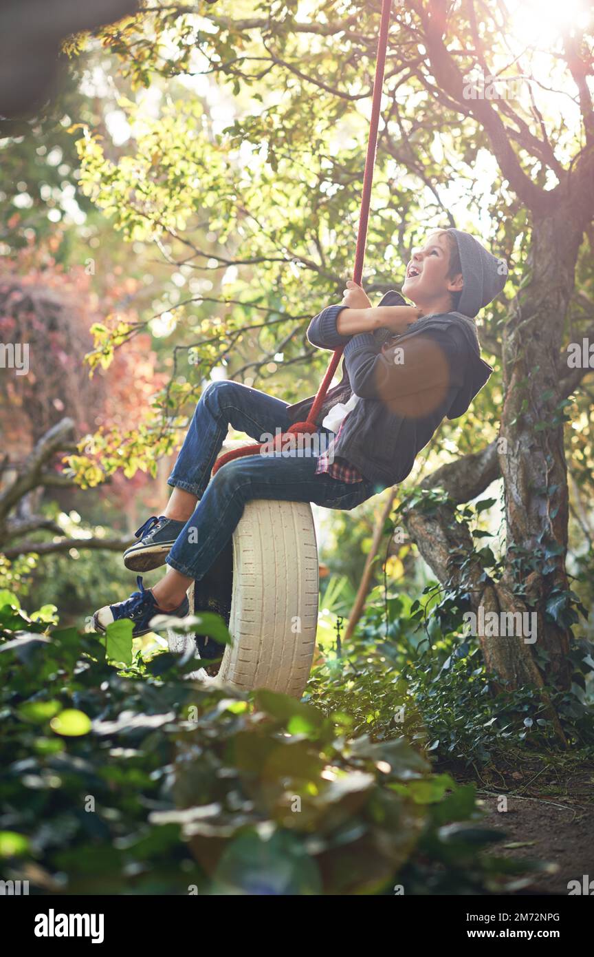 Dont forget to play. A preteen boy swinging on a tyre swing in the garden. Stock Photo