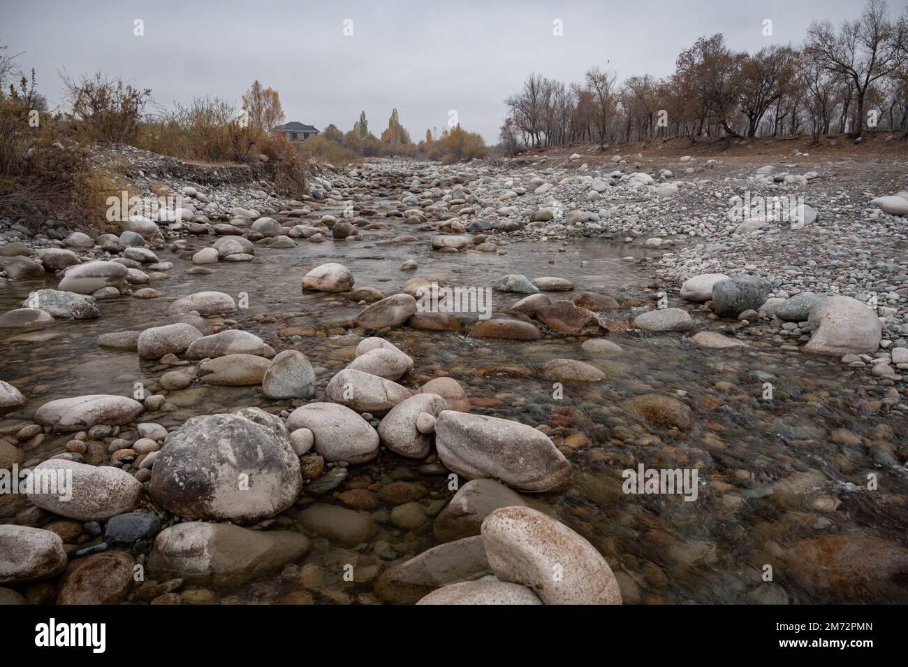 Slow and not deep mountain river with rounded stones Stock Photo
