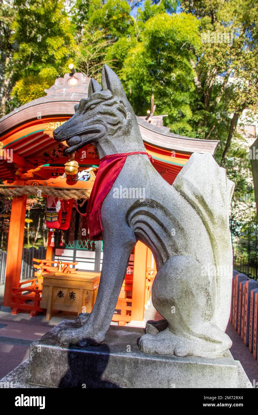Kobe Japan Dec 6th 2022: Statue of a kitsune adorned with a red votive bib in the Inari Ōkami in Ikuta Shrine. Stock Photo