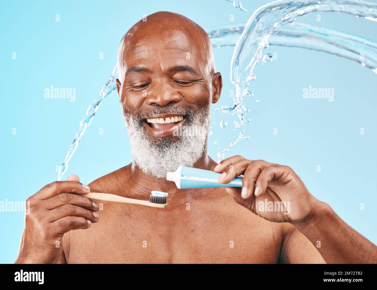 Water, splash and man with dental care in a studio for mouth health and wellness. Toothpaste, toothbrush and elderly African guy brushing his teeth Stock Photo