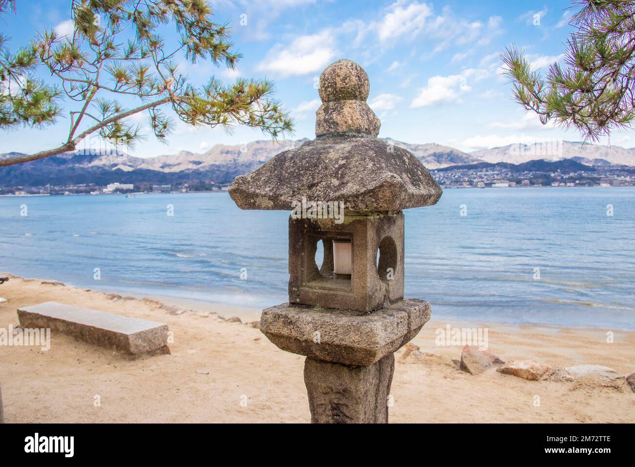 The stone latern in the island of Miyajima. Background is the city view of Miyajima guchi Japan. Stock Photo
