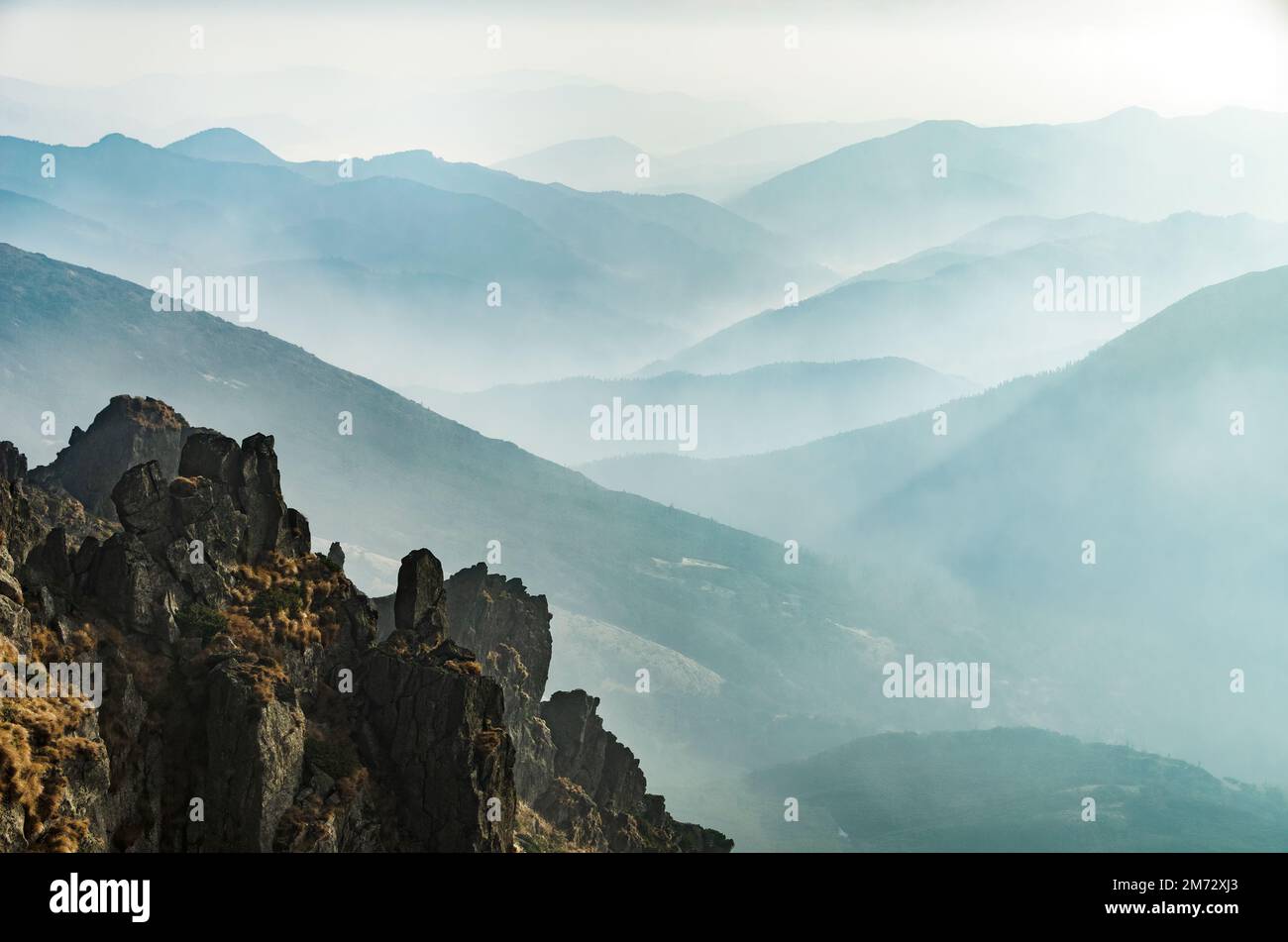 Misty mountain valley with light blue mountain silhouettes in the fog