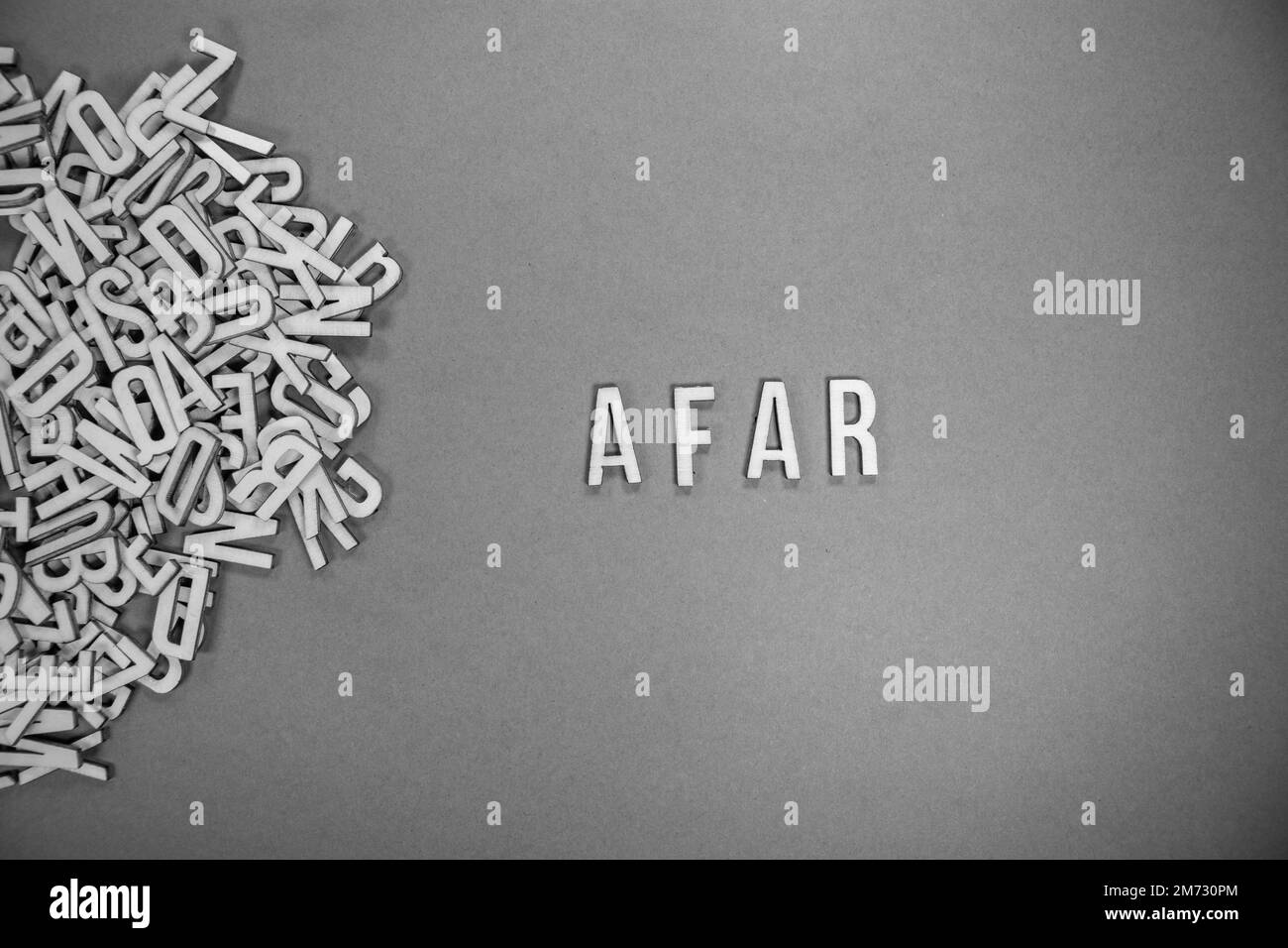 AFAR in wooden English language capital letters spilling from a pile of letters on a blue background - black and white Stock Photo
